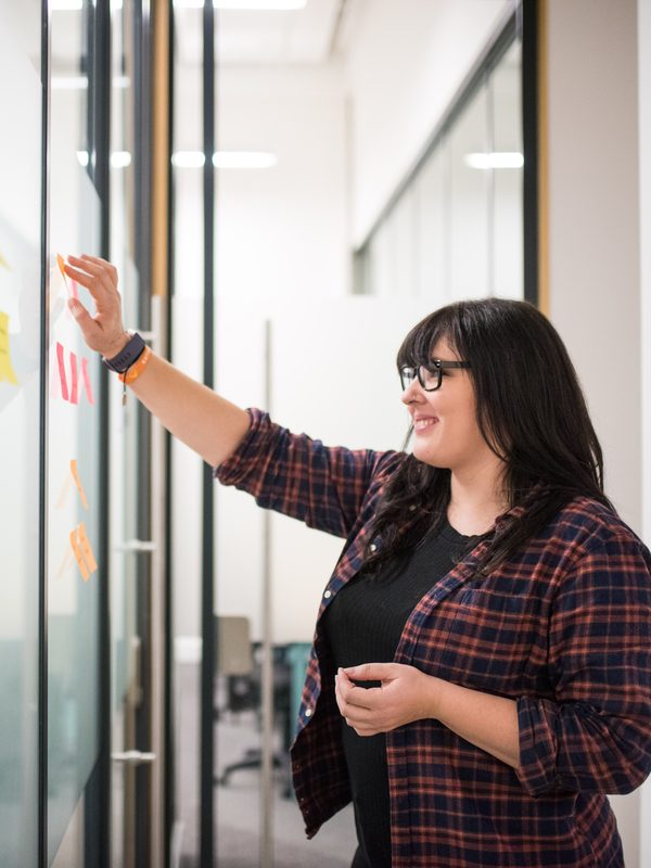 A colleague putting sticky notes on a glass wall during a planning session