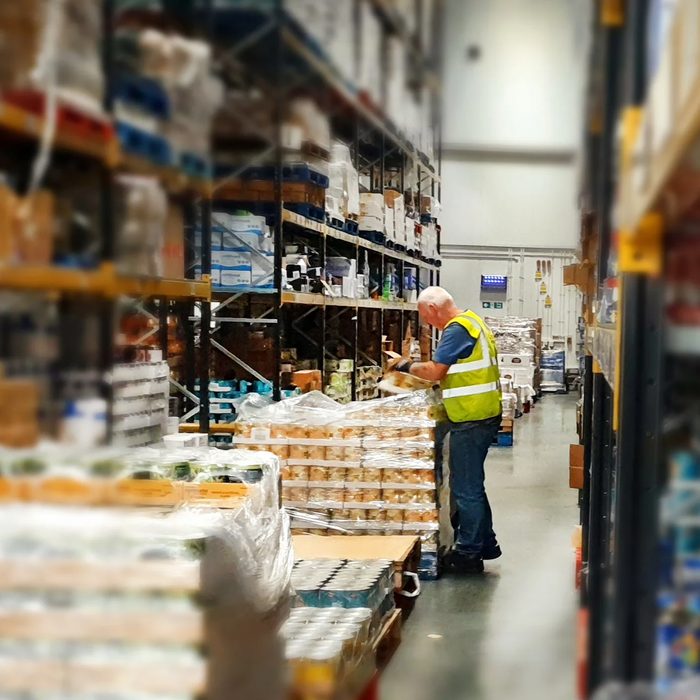 A warehouse worker checking stock on pallets in a wholesale depot