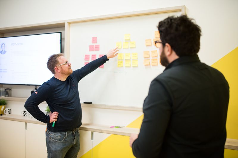 Matt moving sticky notes on a whiteboard during a planning session