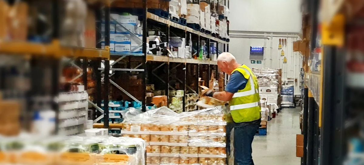 A warehouse worker checking stock on pallets in a wholesale depot